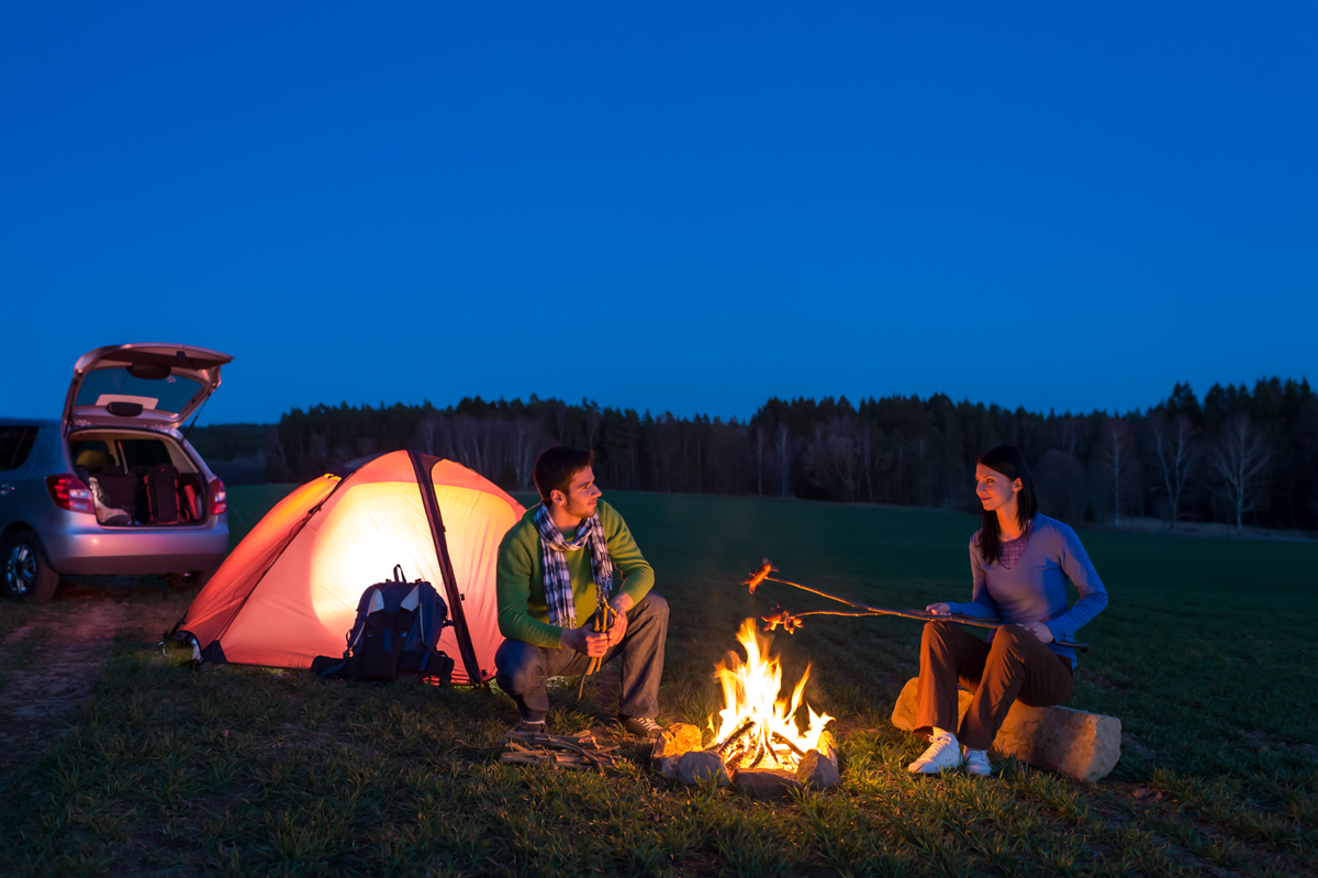 Couple sitting by campfire and tent