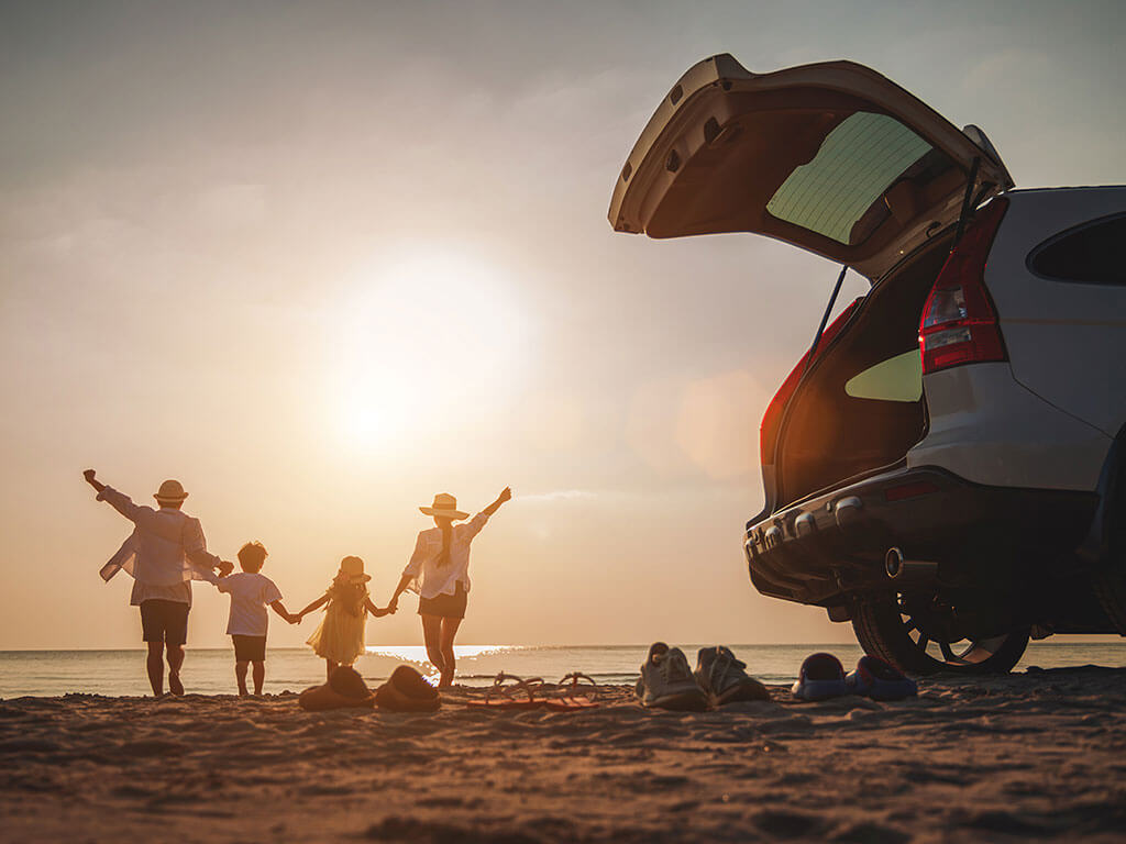 Family with hatchback car on beach