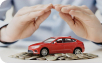 Hands held protectively over a small red car model placed on a pile of coins, symbolizing car insurance or financial protection.